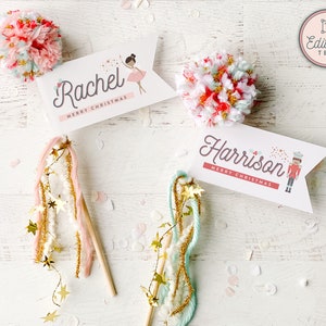 Pode incluir: Duas etiquetas de presente com tema natalino com pompons rosa e azul, glitter dourado e barbante. As etiquetas apresentam os nomes "Rachel" e "Harrison" com o texto "Feliz Natal".