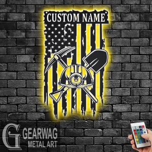 May include: A yellow illuminated metal sign with a distressed American flag design. The flag has a pickaxe, shovel, and miner's helmet superimposed on it. The sign also has the text "CUSTOM NAME" at the top.