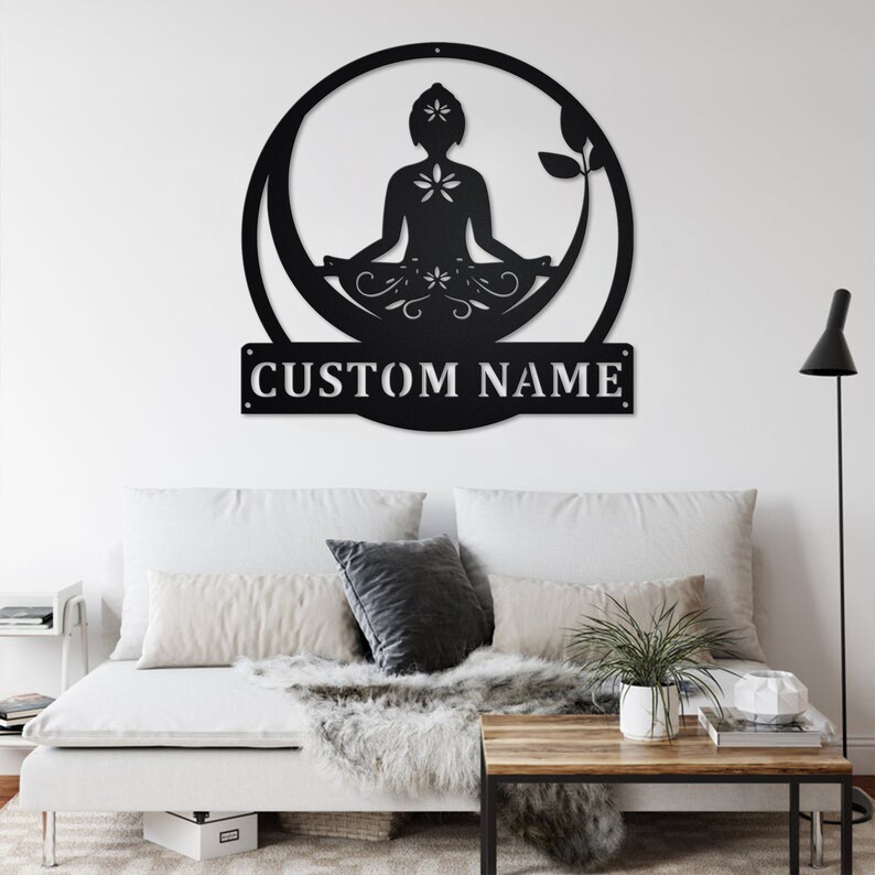 K&ouml;nnte beinhalten: Schwarze Wandkunst aus Metall mit einer stilisierten Silhouette einer Person in einer Yoga-Pose, umgeben von floralen Designs. Die Kunst enth&auml;lt eine personalisierte Namensschilder, die "CUSTOM NAME" lautet.
