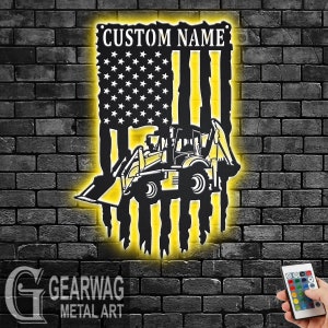 May include: Metal wall art featuring an American flag design with a construction vehicle silhouette. The flag has a yellow glow effect, and the text "CUSTOM NAME" is at the top. The art is mounted on a dark brick wall.