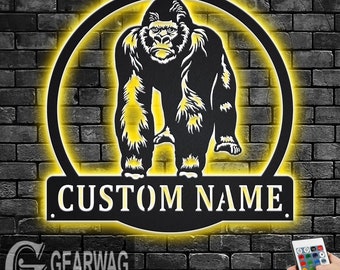 May include: Black metal wall art featuring a gorilla silhouette in a circle with a yellow glow. The art includes a customizable nameplate that reads "CUSTOM NAME".