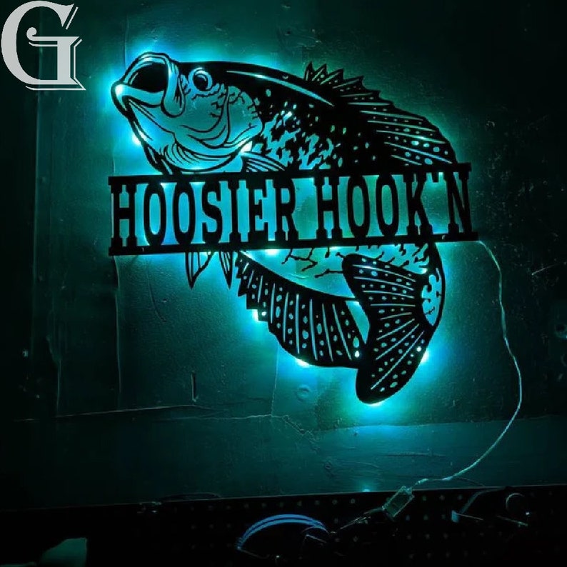 May include: A black metal sign with a silhouette of a fish and the text "HOOSIER HOOK'N". The sign is illuminated with blue lights.