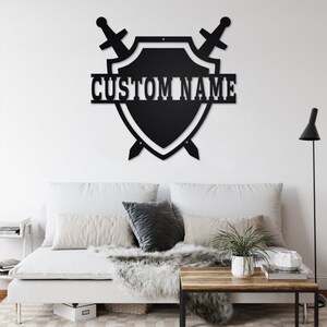 May include: Black metal wall decor featuring a shield with two crossed swords and the text "CUSTOM NAME" in white.