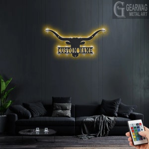 May include: A black metal silhouette of a longhorn steer head with horns, with a custom nameplate below. The silhouette is illuminated with warm white LED lights. The lights can be changed to different colors using a remote control.