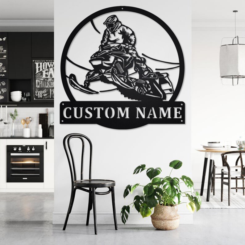 May include: Black metal wall art featuring a silhouette of a person riding a snowmobile. The art is circular and includes the text "CUSTOM NAME" at the bottom.