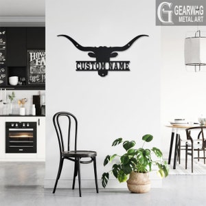 May include: Black metal wall art featuring a longhorn steer head silhouette with a personalized nameplate that reads "CUSTOM NAME". The art is mounted on a white wall in a modern kitchen setting.