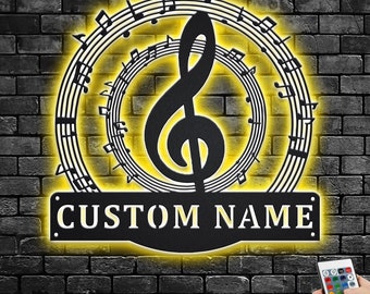 Puede incluir: Decoración de pared de metal negro con una clave de sol y notas musicales en un círculo. La decoración está iluminada con luces LED amarillas y tiene una placa de nombre personalizada que dice "CUSTOM NAME".