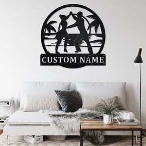 May include: Black metal silhouette of a couple dancing on a beach with palm trees and waves. The silhouette is in a circle with the text "CUSTOM NAME" below it.