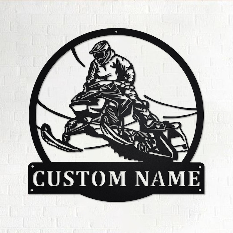 May include: Black metal silhouette of a person riding a snowmobile in a circle with the words "CUSTOM NAME" below.