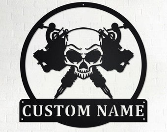 May include: Black metal wall art featuring a skull with two crossed tattoo machines. The art includes a personalised nameplate that reads "CUSTOM NAME".