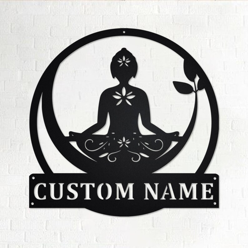 K&ouml;nnte beinhalten: Schwarze Wandkunst aus Metall mit einer stilisierten Silhouette einer Person in einer Yoga-Pose, umgeben von einem Kreis und floralen Designs. Die Kunst enth&auml;lt eine personalisierte Namensschilder mit dem Text "CUSTOM NAME".