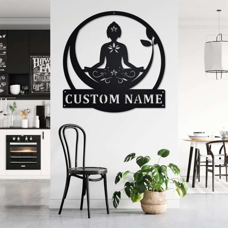 K&ouml;nnte beinhalten: Schwarze Wandkunst aus Metall mit einer Silhouette einer Person in einer Yoga-Pose mit einem floralen Design. Die Kunst enth&auml;lt eine anpassbare Namensschilder mit dem Text "CUSTOM NAME".