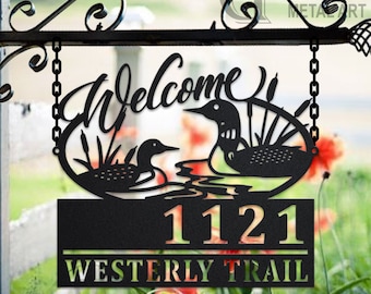 Può includere: Un cartello di benvenuto in metallo nero con due uccelli tuffatori e il testo "Welcome" in un carattere decorativo. Il cartello include anche il numero civico "1121" e il nome della strada "Westerly Trail".