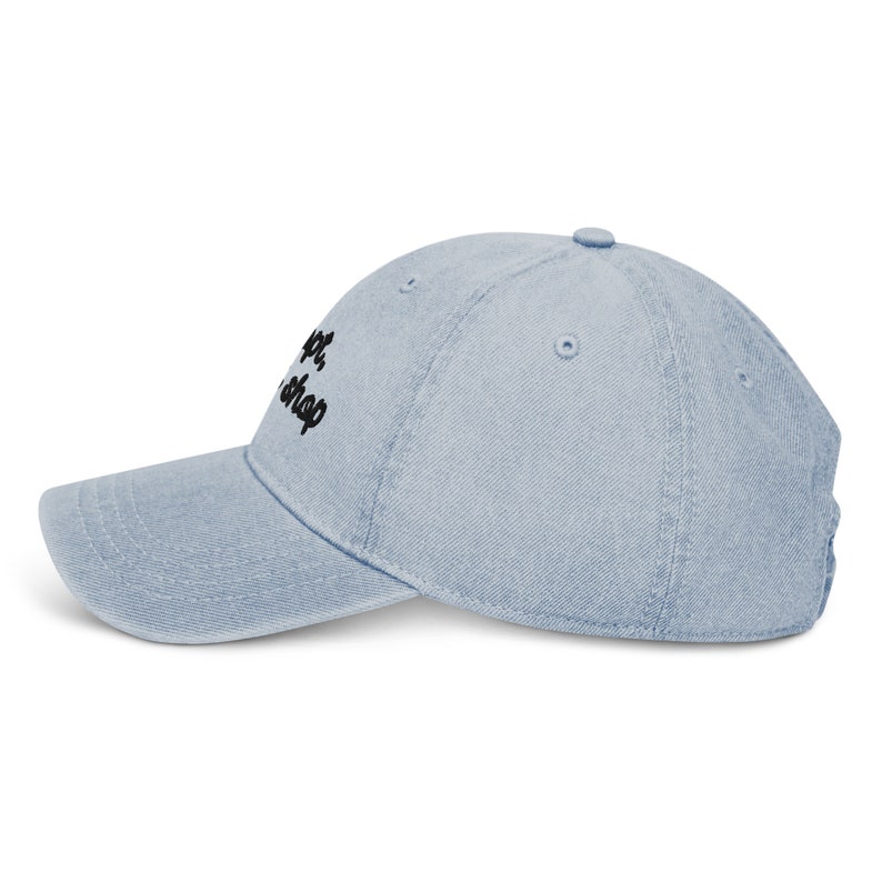May include: A light blue denim baseball cap with black embroidered text that reads "Craft Shop".