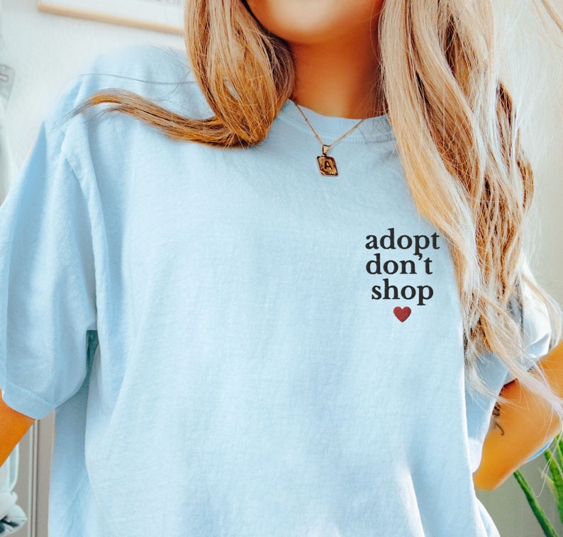 May include: A light blue t-shirt with the text "adopt don't shop" and a small red heart.