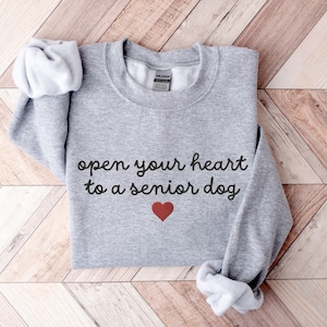 May include: Gray sweatshirt with the text "open your heart to a senior dog" in black cursive lettering and a red heart below the text.