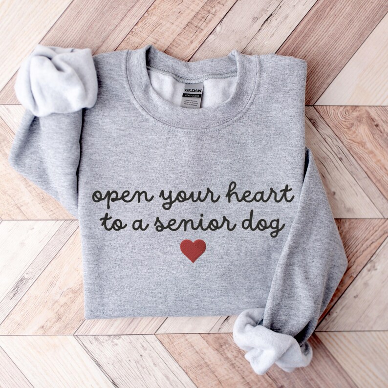 May include: Gray sweatshirt with the text "open your heart to a senior dog" in black cursive lettering and a red heart below the text.