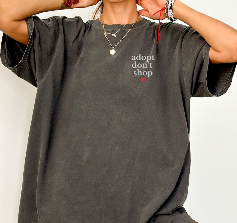 May include: A dark gray t-shirt with the text "adopt don't shop" and a small red heart.
