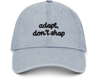 May include: A light blue denim baseball cap with black embroidered text that reads "adopt, don't shop".