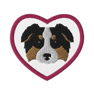 May include: A pink heart-shaped patch with an embroidered image of a black, brown, and white dog's face.