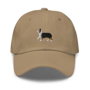 May include: A tan baseball cap with an embroidered image of a black, white, and brown Australian Shepherd.