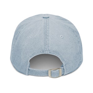 May include: A light blue denim baseball cap with a silver buckle closure.