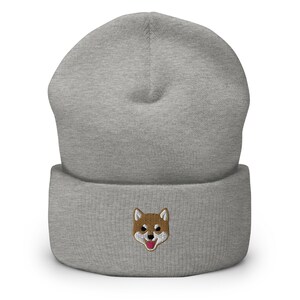 以下が含まれることがあります： 茶色と白の刺繍で柴犬の顔が施された灰色のビーニー