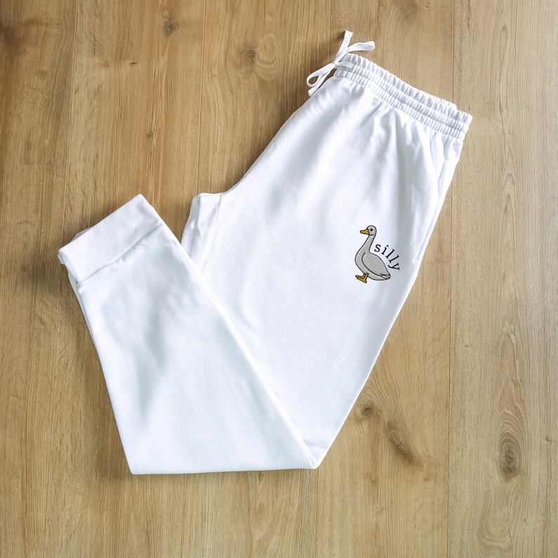 May include: White sweatpants with a gray goose and the word "silly" embroidered on the left leg.