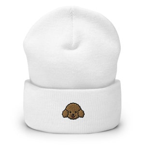 Puede incluir: Gorro de punto blanco con una cara de caniche bordada en marr&oacute;n.