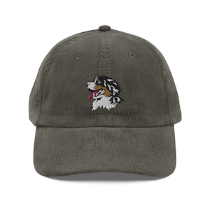 May include: A green corduroy baseball cap with an embroidered image of a Bernese Mountain Dog.