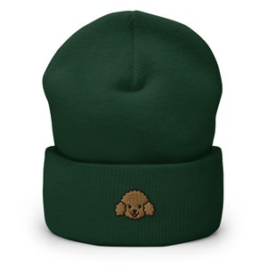 Puede incluir: Un gorro de lana verde oscuro con un rostro de caniche bordado en marr&oacute;n en la parte delantera.