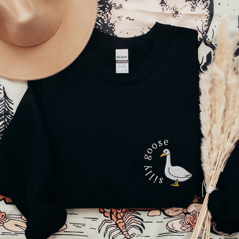 May include: Black sweatshirt with a white embroidered goose and the text "Silly Goose" in a circle around it.