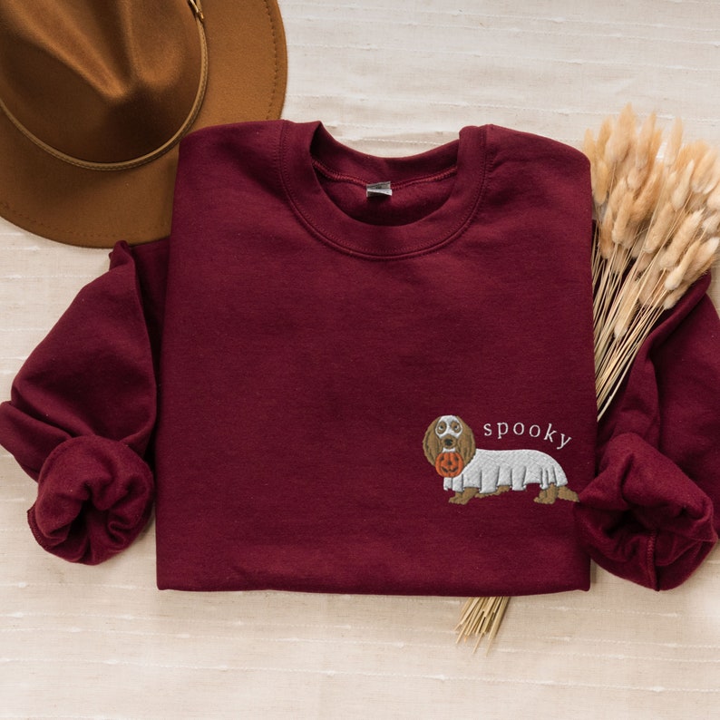May include: Burgundy sweatshirt with a ghost costume dachshund graphic and the text "spooky" on the front.