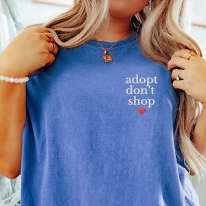 May include: A blue t-shirt with the text "adopt don't shop" in white lettering and a small red heart.