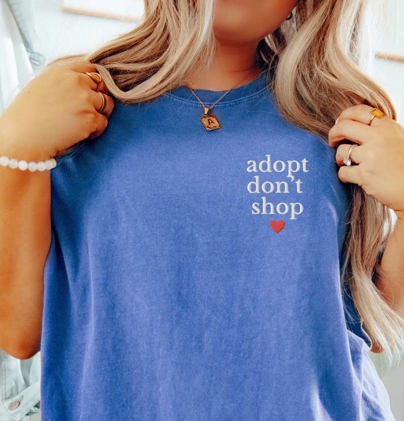 May include: A blue t-shirt with the text "adopt don't shop" in white lettering and a small red heart.