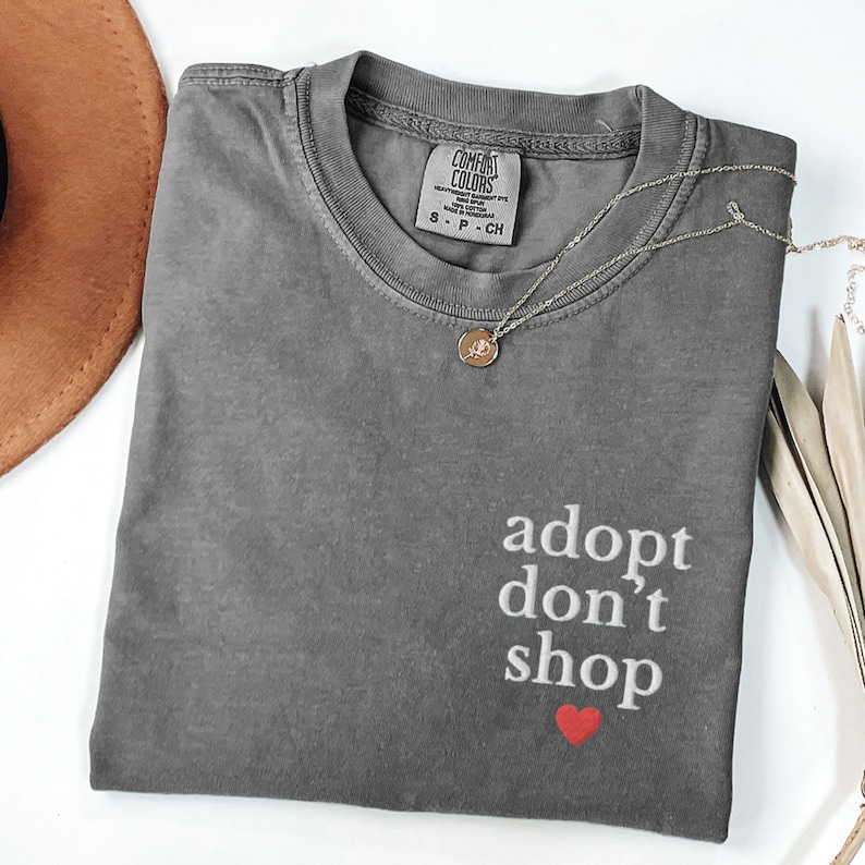 May include: Gray t-shirt with the text "adopt don't shop" in white with a red heart underneath.