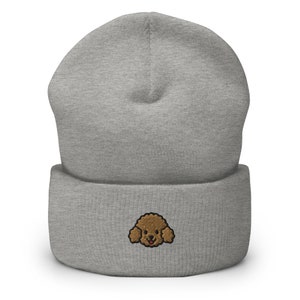 Puede incluir: Gorro gris con una cara de caniche bordada en marr&oacute;n en la parte delantera.