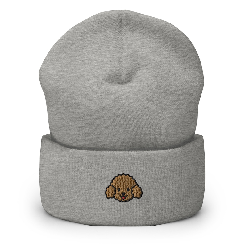 Puede incluir: Gorro gris con una cara de caniche bordada en marr&oacute;n en la parte delantera.