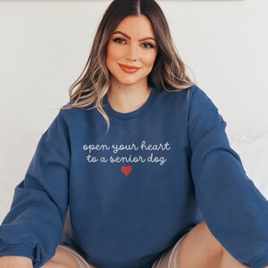 May include: A navy blue sweatshirt with the text "open your heart to a senior dog" in white lettering and a red heart.
