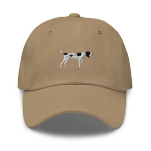 May include: A tan baseball cap with an embroidered black and white dog on the front.