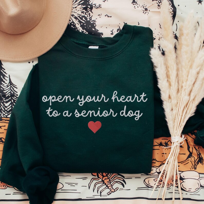 Embroidered open your heart to a senior dog with heart on a unisex Gildan 18000 forest green sweatshirt