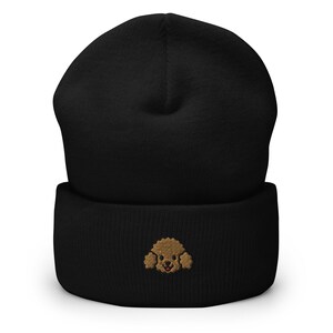 Puede incluir: Gorro negro con una cara de caniche bordada en marr&oacute;n en la parte delantera.