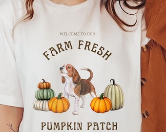 May include: White t-shirt with a brown graphic that says "Welcome to our Farm Fresh Pumpkin Patch" with a beagle dog and pumpkins. The text also says "Premium Quality".