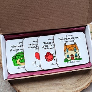 May include: Set of four white coasters with black text and illustrations. The coasters feature quotes from classic literature, including "Wherever you are is my home" from Jane Eyre, "But he who would grasp the thorn should never crave the rose" from The Natural, "Whatever is done is done" from Wuthering Heights, and "There was a world of taking a walk" from Jane Eyre.