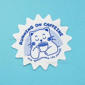 May include: White sticker with a blue starburst design. The sticker features a cartoon cat holding a cup of coffee and the text "Running on caffeine and questionable life choices".