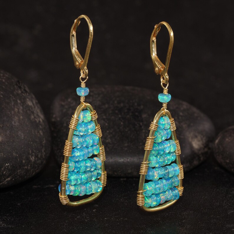 K&ouml;nnte beinhalten: Ein Paar goldfarbene Ohrringe mit Tropfendesign. Die Ohrringe haben Reihen aus kleinen, hellblauen Perlen, die in einem goldfarbenen Drahtrahmen eingeschlossen sind. Die Ohrringe haben einen B&uuml;gelverschluss und eine kleine blaue Perle oben.