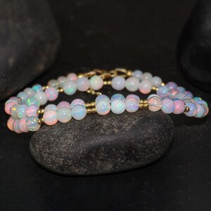May include: A double strand necklace made of iridescent white opal beads separated by gold spacers.