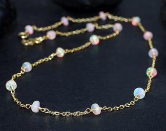 May include: A delicate gold chain necklace with small white opal beads. The necklace is approximately 18 inches long and features a simple, elegant design.