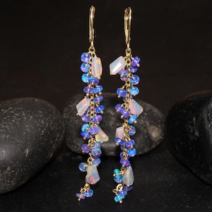May include: A pair of long, gold dangle earrings with a cascade of iridescent opal and purple amethyst stones.