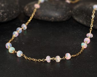 May include: A delicate gold chain necklace with small, round, iridescent opal beads. The necklace is approximately 18 inches long.